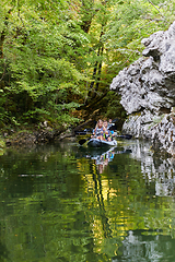 Image showing A group of friends enjoying having fun and kayaking while exploring the calm river, surrounding forest and large natural river canyons