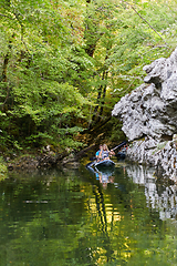 Image showing A group of friends enjoying having fun and kayaking while exploring the calm river, surrounding forest and large natural river canyons