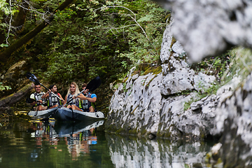 Image showing A young couple enjoying an idyllic kayak ride in the middle of a beautiful river surrounded by forest greenery