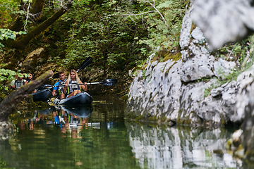 Image showing A young couple enjoying an idyllic kayak ride in the middle of a beautiful river surrounded by forest greenery