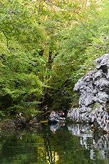 Image showing A young couple enjoying an idyllic kayak ride in the middle of a beautiful river surrounded by forest greenery