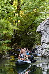 Image showing A group of friends enjoying having fun and kayaking while exploring the calm river, surrounding forest and large natural river canyons