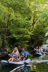 Image showing A group of friends enjoying having fun and kayaking while exploring the calm river, surrounding forest and large natural river canyons