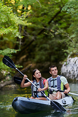 Image showing A young couple enjoying an idyllic kayak ride in the middle of a beautiful river surrounded by forest greenery