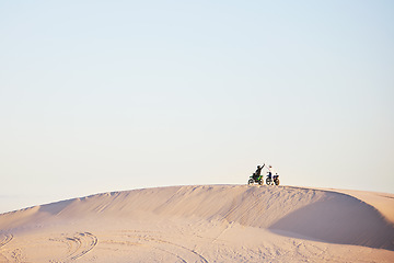 Image showing Desert blue sky, motorbike and sports people high five, excited celebrate travel, teamwork or off road achievement. Motorcycle adventure, mockup winner or athlete driver collaboration on sand dunes