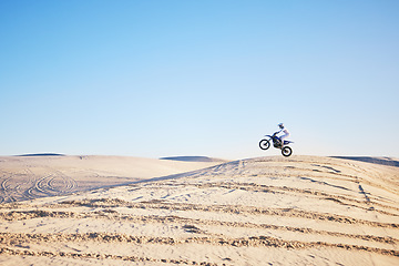 Image showing Desert, bike jump or sports person travel, agile and air trick on sand hill adventure, exercise or training. Motorcycle challenge, sky or extreme athlete risk, freestyle competition or skill training