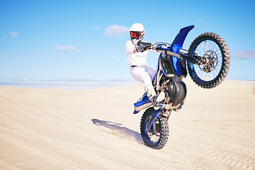 Image showing Bike, freedom and balance with a man in the desert for fitness or an adrenaline hobby on a blue sky. Motorcycle, training and summer with a male sports athlete riding a vehicle in Dubai for energy