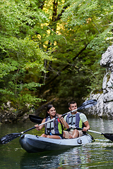 Image showing A young couple enjoying an idyllic kayak ride in the middle of a beautiful river surrounded by forest greenery