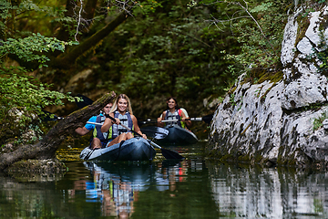 Image showing A group of friends enjoying having fun and kayaking while exploring the calm river, surrounding forest and large natural river canyons