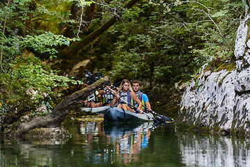 Image showing A group of friends enjoying having fun and kayaking while exploring the calm river, surrounding forest and large natural river canyons