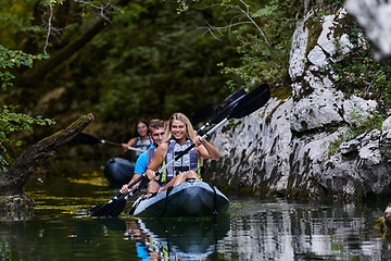 Image showing A group of friends enjoying having fun and kayaking while exploring the calm river, surrounding forest and large natural river canyons