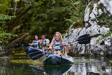 Image showing A group of friends enjoying having fun and kayaking while exploring the calm river, surrounding forest and large natural river canyons