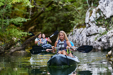 Image showing A group of friends enjoying having fun and kayaking while exploring the calm river, surrounding forest and large natural river canyons