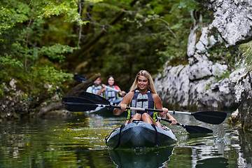 Image showing A group of friends enjoying having fun and kayaking while exploring the calm river, surrounding forest and large natural river canyons