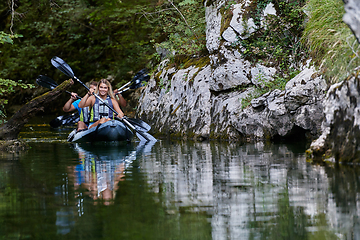 Image showing A young couple enjoying an idyllic kayak ride in the middle of a beautiful river surrounded by forest greenery