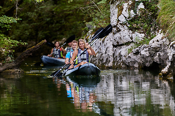 Image showing A group of friends enjoying having fun and kayaking while exploring the calm river, surrounding forest and large natural river canyons