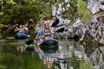 Image showing A group of friends enjoying having fun and kayaking while exploring the calm river, surrounding forest and large natural river canyons