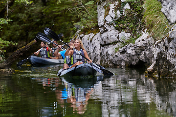 Image showing A group of friends enjoying having fun and kayaking while exploring the calm river, surrounding forest and large natural river canyons