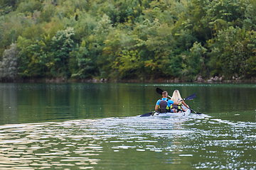 Image showing A young couple enjoying an idyllic kayak ride in the middle of a beautiful river surrounded by forest greenery