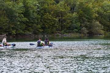 Image showing A young couple enjoying an idyllic kayak ride in the middle of a beautiful river surrounded by forest greenery