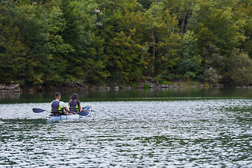 Image showing A young couple enjoying an idyllic kayak ride in the middle of a beautiful river surrounded by forest greenery