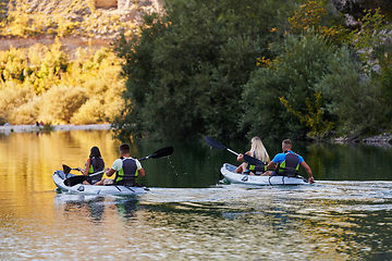 Image showing A group of friends enjoying having fun and kayaking while exploring the calm river, surrounding forest and large natural river canyons