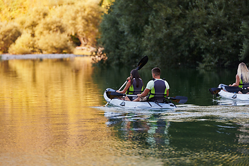 Image showing A group of friends enjoying having fun and kayaking while exploring the calm river, surrounding forest and large natural river canyons