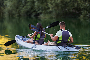 Image showing A young couple enjoying an idyllic kayak ride in the middle of a beautiful river surrounded by forest greenery