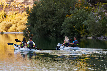 Image showing A group of friends enjoying having fun and kayaking while exploring the calm river, surrounding forest and large natural river canyons