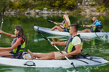 Image showing A group of friends enjoying having fun and kayaking while exploring the calm river, surrounding forest and large natural river canyons