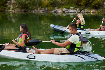 Image showing A group of friends enjoying having fun and kayaking while exploring the calm river, surrounding forest and large natural river canyons