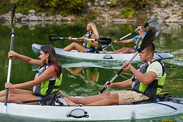 Image showing A group of friends enjoying having fun and kayaking while exploring the calm river, surrounding forest and large natural river canyons