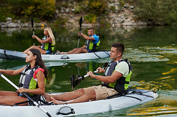 Image showing A group of friends enjoying having fun and kayaking while exploring the calm river, surrounding forest and large natural river canyons