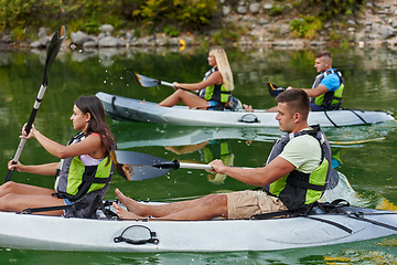 Image showing A group of friends enjoying having fun and kayaking while exploring the calm river, surrounding forest and large natural river canyons