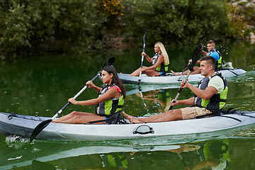 Image showing A group of friends enjoying having fun and kayaking while exploring the calm river, surrounding forest and large natural river canyons