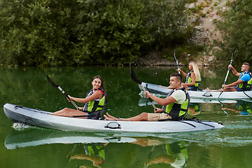 Image showing A group of friends enjoying having fun and kayaking while exploring the calm river, surrounding forest and large natural river canyons