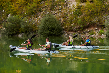 Image showing A group of friends enjoying having fun and kayaking while exploring the calm river, surrounding forest and large natural river canyons