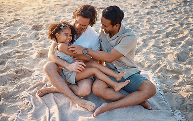 Image showing Gay father, play and girl at beach with love, tickling or hug for vacation, laughing or outdoor in sunshine. LGBTQ parents, young kid and adoption with family, holiday or comic conversation in summer