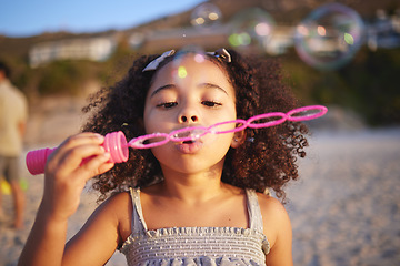 Image showing Girl child, beach and blowing bubbles with playing, outdoor and freedom on sand, games and thinking in nature. Female kid, soap and water with plastic toys with wind, summer sunshine and vacation