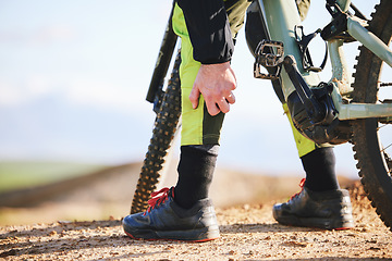 Image showing Hand, cycling and leg pain with a person on a bike outdoor on a dirt track for fitness or exercise. Sports, training injury injury and an athlete on a bike with a medical emergency or accident