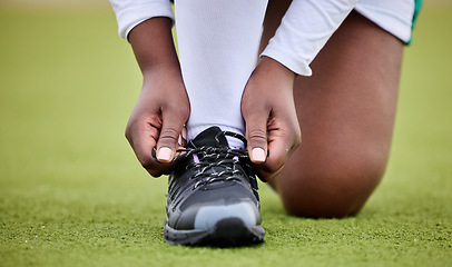 Image showing Lace shoes, sports person and field for training, performance or workout on grass turf. Closeup hands of athlete tie sneakers, footwear and feet to start exercise for game, fitness or contest on lawn