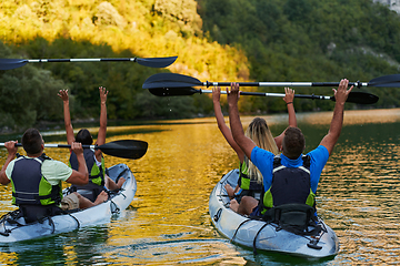 Image showing A group of friends enjoying having fun and kayaking while exploring the calm river, surrounding forest and large natural river canyons