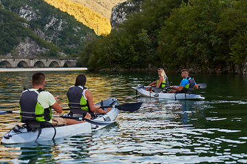 Image showing A group of friends enjoying having fun and kayaking while exploring the calm river, surrounding forest and large natural river canyons