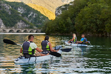 Image showing A group of friends enjoying having fun and kayaking while exploring the calm river, surrounding forest and large natural river canyons