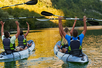 Image showing A group of friends enjoying having fun and kayaking while exploring the calm river, surrounding forest and large natural river canyons