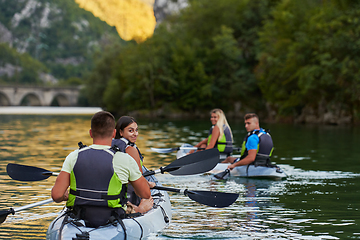 Image showing A group of friends enjoying having fun and kayaking while exploring the calm river, surrounding forest and large natural river canyons