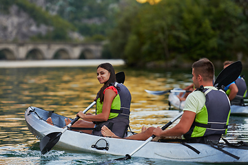 Image showing A group of friends enjoying having fun and kayaking while exploring the calm river, surrounding forest and large natural river canyons