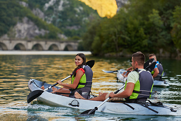 Image showing A group of friends enjoying having fun and kayaking while exploring the calm river, surrounding forest and large natural river canyons