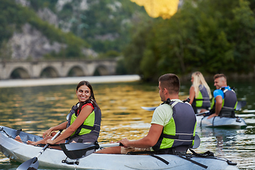 Image showing A group of friends enjoying having fun and kayaking while exploring the calm river, surrounding forest and large natural river canyons