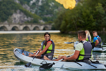 Image showing A group of friends enjoying having fun and kayaking while exploring the calm river, surrounding forest and large natural river canyons